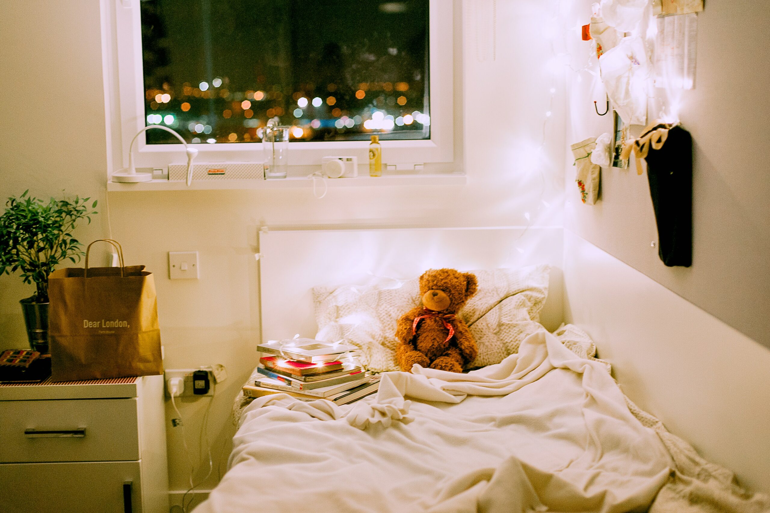 photo of children's bed with a teddy bear and twinkle lights.